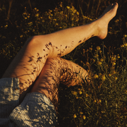 gros plan sur les jambes d'une personne allongée dans un champ de fleurs sauvages