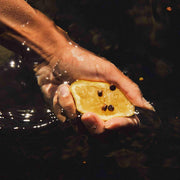Bergamote pressée par une main dans l'eau, l'un des ingrédients du parfum naturel l'Eau de Floratropia