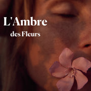 Photo médaillon du parfum naturel L'Ambre des Fleurs représentant un visage féminin qui tient une fleur dans la bouche, en teint chaud